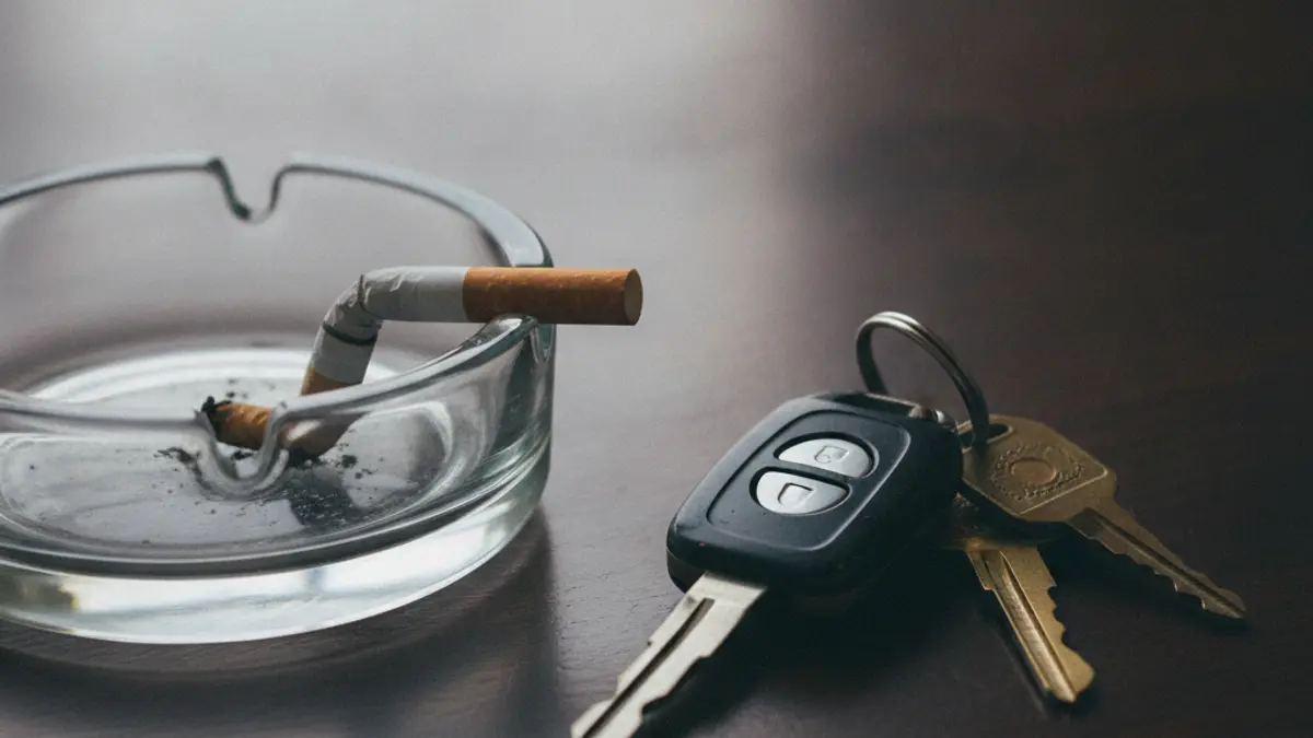 Cigarro apagado num cinzeiro, ao lado de chaves de carro